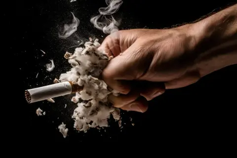 Puño aplastando un cigarrillo con humo, simbolizando cómo quitar el olor a tabaco de la casa.