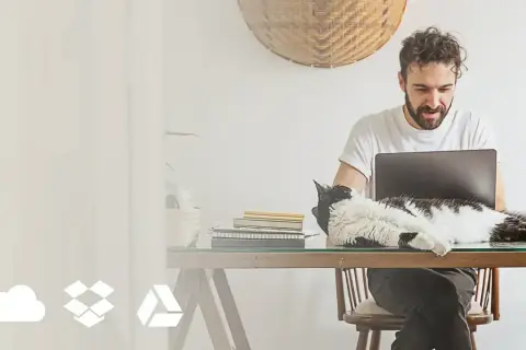 Mężczyzna pracuje przy laptopie, a kot leży na biurku. Ikony chmury, pudełka i trójkąta symbolizują online photo storage options.