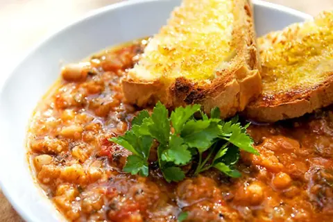 En närbild av en skål med mustig ribollita, toppad med rostat bröd och färsk persilja. Ett perfekt ribollita recept för en kall dag.