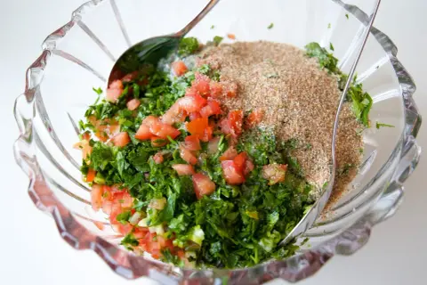 En skål med färska ingredienser för Zeinas tabbouleh: hackad persilja, tomat och bulgur.
