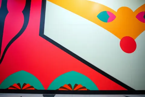 Żywe, geometryczne dzieła w stylu art déco z dominującymi czerwienią i żółcią, ozdobione czarnymi liniami i turkusowymi akcentami.