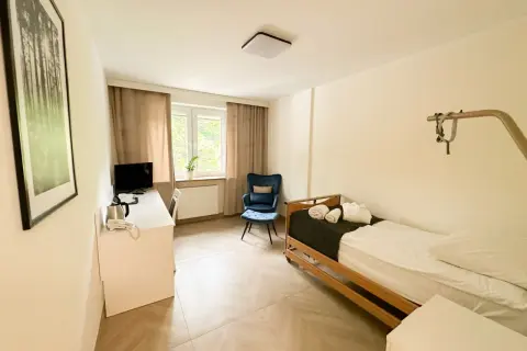 Pokój hotelowy z łóżkiem, biurkiem, fotelem i obrazem z lasem.