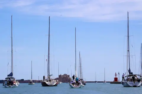 Veleggiate serene nella marina d'Angelo, con barche che solcano le acque azzurre sotto un cielo limpido.