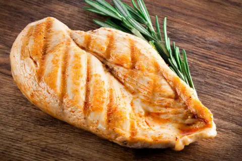 Grillowana pierś z kurczaka z rozmarynem na drewnianej desce.