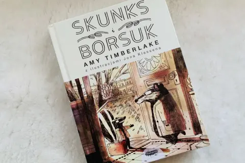 Skunks i Borsuk – idealne książki na dobranoc. Ilustracja przedstawia dwóch borsuków w płaszczach, jeden z walizką, gotowych na przygodę.