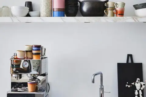 Stilvolle Kaffeebar Ideen: Chrom-Espressomaschine mit bunten Tassen, Marmorregal mit Geschirr und ein Stormtrooper-Dekor.