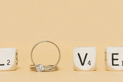 Un anillo inicial de oro con un diamante, junto a cubos que forman la palabra "LOVE".