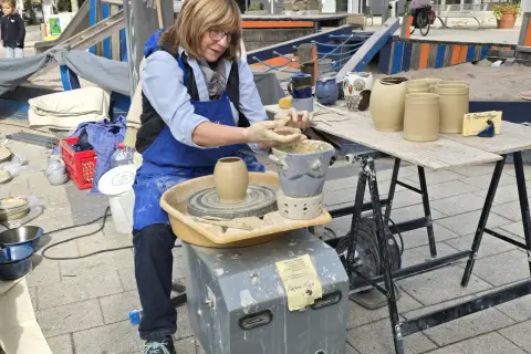 Töpferin am Werk am Hafenmarkt Heilbronn. Sie formt mit geübten Händen Ton auf ihrer Töpferscheibe.