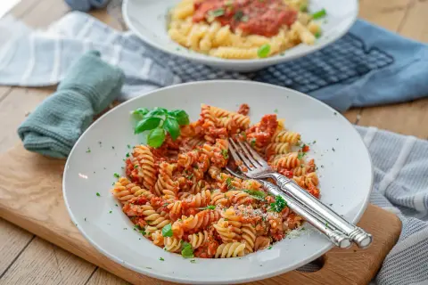 Eine köstliche Thunfisch Pasta mit Fusilli, Tomatensauce und frischem Basilikum, garniert mit Petersilie und Parmesan.