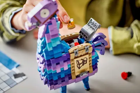 Ręce składają kolorową, klockową **lamę z Fortnite**. Otwiera się jej brzuch, odsłaniając skarb.