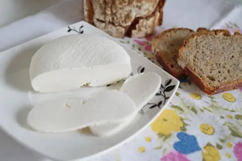 Świeży ser di bufala na talerzyku, obok kromki chleba.