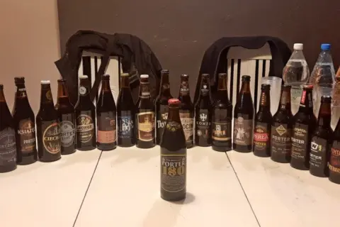 Stół zastawiony butelkami i puszkami piwa, idealny na dzień porteru bałtyckiego. Widać różne marki i etykiety.