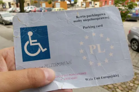 Karta parkingowa dla niepełnosprawnych z symbolem wózka inwalidzkiego i gwiazdkami UE.