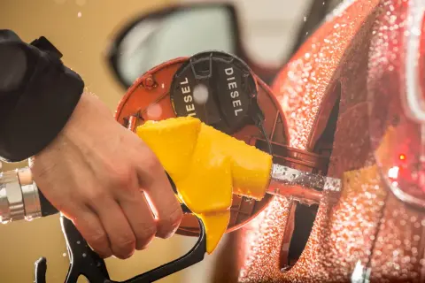 Mano che inserisce la pompa gialla nel serbatoio con la scritta "DIESEL". Attenzione a non confondere la benzina nel diesel!