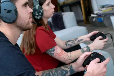 Ein Paar spielt konzentriert auf der PS4, bis die PS4 abgeschaltet wird.
