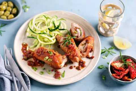 Herzhafte involtini vom Kalb mit Zucchini-Spaghetti und einer würzigen Tomatensauce, garniert mit Rosmarin.