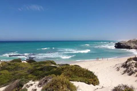 Türkisblaues Meer und Sanddünen im De Hoop Nature Reserve. Kleine Figuren genießen den Strand.