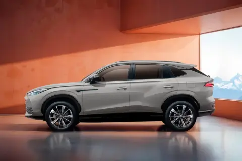 Elegancki SUV marki MG w kolorze piaskowym, zaparkowany w nowoczesnym wnętrzu z widokiem na góry.