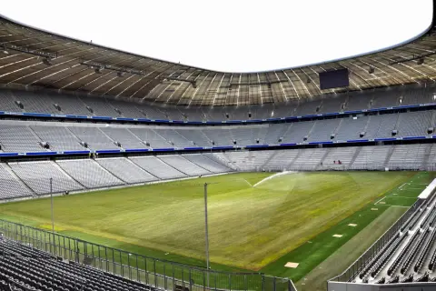 Pusta Allianz Arena, z zieloną murawą i trybunami czekającymi na kibiców.