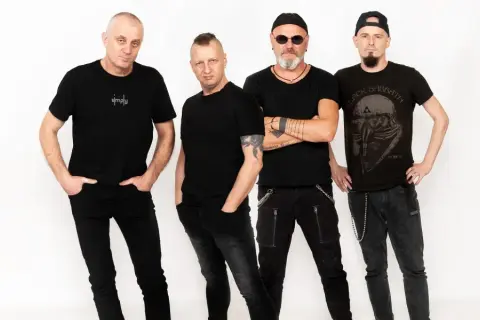 Czterech mężczyzn w czarnych ubraniach, tworzących zespół. Jeden z nich ma na koszulce napis "simply", inny koszulkę z logo Black Sabbath.