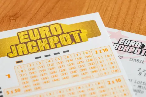 Kupony Eurojackpot z polami do zaznaczania liczb na drewnianym tle.