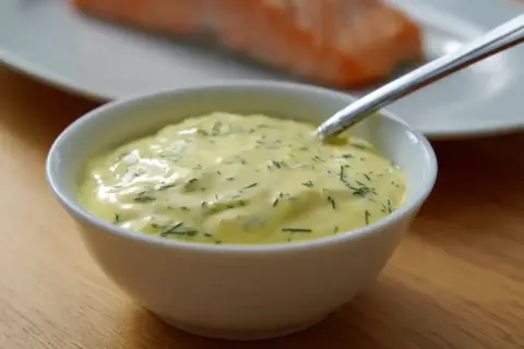 Krämig sås till lax, med dill och andra örter, serverad i en vit skål. En perfekt sås till din laxrätt.