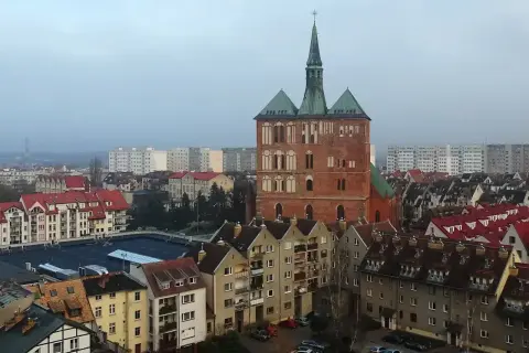 Widok na ceglaną wieżę kościoła i zabudowania miejskie Kołobrzegu.