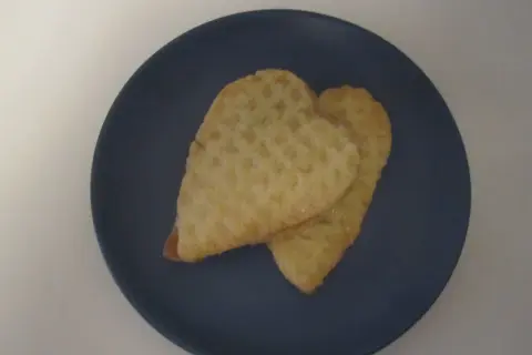 Två hjärtformade kex med socker på en mörkblå tallrik. Perfekta för parisare recept.