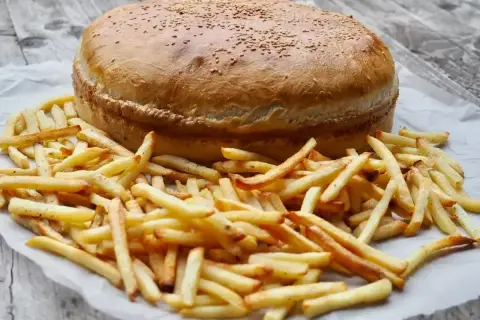 Ogromny burger z sezamem i złociste frytki, gotowe do podania. Ile piec burgery w piekarniku? Ten wygląda na gotowego!