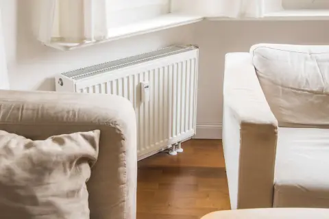 Gemütliche, helle Couch vor einer weißen Heizung, bereit für entspannte Stunden.