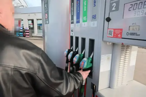 Mężczyzna w czarnej kurtce sięga po dystrybutor z napisem "verva diesel" na stacji paliw.