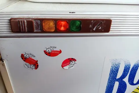 Stara lodówka Polar z kontrolkami i pokrętłem termostatu. Na drzwiach naklejki z biedronkami i napisem "Malinowy".