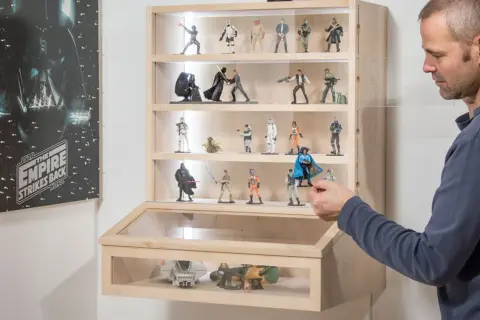 Mann arrangiert Star Wars Figuren in einer selbstgebauten Acryl Vitrine.