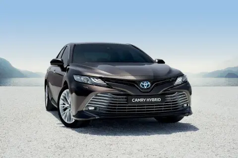 Elegancka, ciemnobrązowa Toyota Camry Hybrid 2020 zaparkowana nad jeziorem, gotowa na podróż.