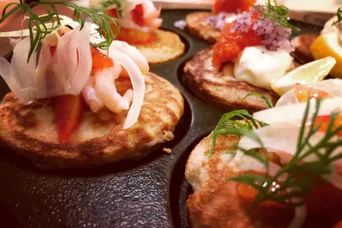 Små, gyllene blinier med räkor, dill och rödlök. Ett perfekt blinier recept för en festlig förrätt.