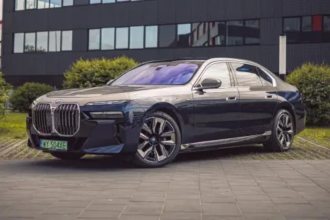 Eleganckie BMW i7 w ciemnym kolorze prezentuje się luksusowo przed nowoczesnym budynkiem.