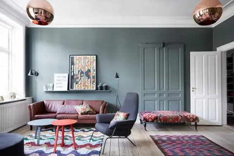 Gemütliche, bunte Wohnung mit Ledersofa, gemusterten Teppichen und auffälligen Lampen.