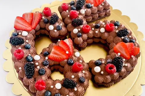 Una torta numero cioccolato, decorata con fragole, lamponi, mirtilli e more.