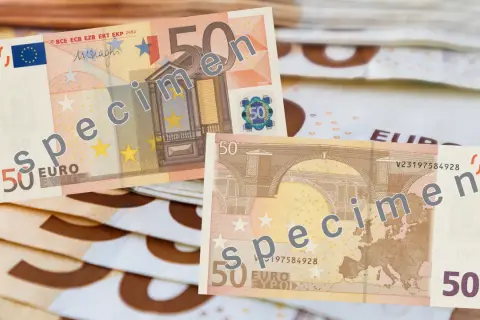 Banknoty 50 euro, oznaczone jako "specimen", leżą na stosie innych banknotów.