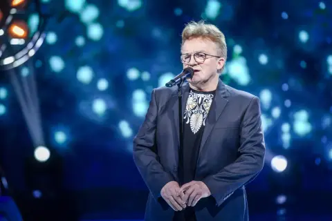 Artysta śpiewa, a na ekranie za nim widać tekst piosenki "Jolka, Jolka pamiętasz".