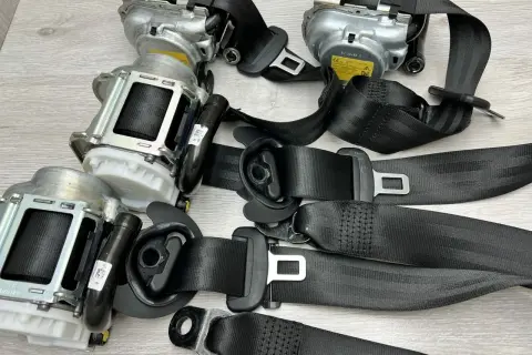 Zastanawiasz się, ile kosztuje wymiana pasów bezpieczeństwa? Na zdjęciu widać kilka kompletnych mechanizmów pasów z klamrami, gotowych do montażu.