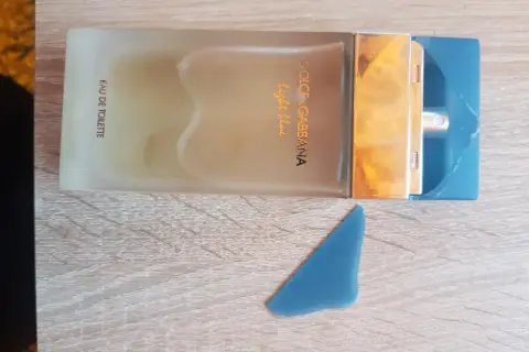 Perfumy Dolce & Gabbana Light Blue, w odcieniu niebieskim, na drewnianym tle.