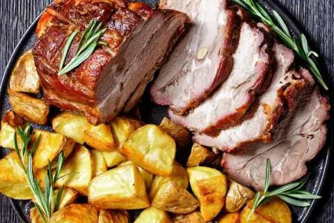 Fettine di maiale al forno morbide, succulente e dorate, servite con patate arrosto e rosmarino fresco.