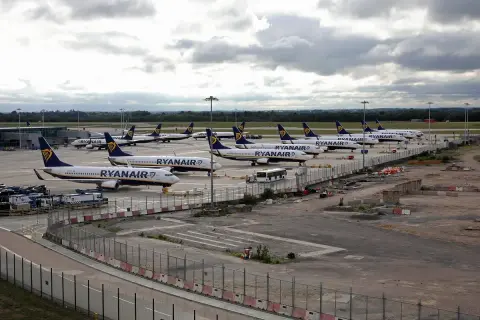 Wiele samolotów Ryanair na płycie lotniska. To typowy widok dla lotnisk w Anglii, gdzie tanie linie lotnicze obsługują duży ruch pasażerski.