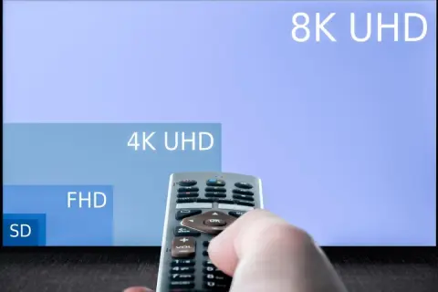 Dłoń trzymająca pilot do telewizora, na ekranie w **hd format** widać porównanie rozdzielczości: 8K UHD, 4K UHD, FHD i SD.