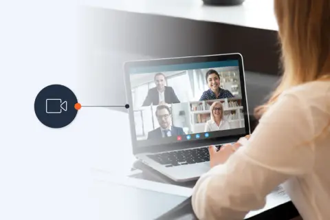 A woman uses a laptop for a video conference, connecting with colleagues via a WebRTC phone call.