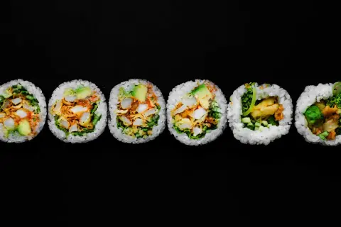 Sześć kawałków futomaki, czyli dużych rolek sushi, z awokado, warzywami i smażonymi kawałkami.