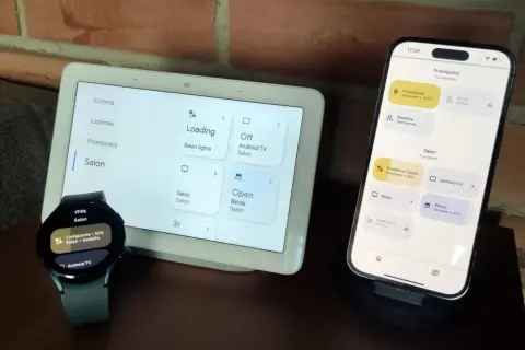 Zegarek z Wear OS i smartfon sterują inteligentnym domem. Na ekranach widać sterowanie oświetleniem i roletami w salonie.