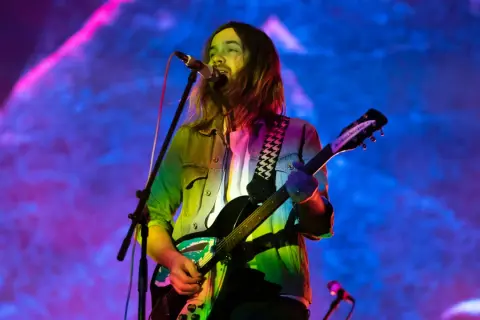Kevin Parker z Tame Impala gra na gitarze podczas koncertu w Warszawie.