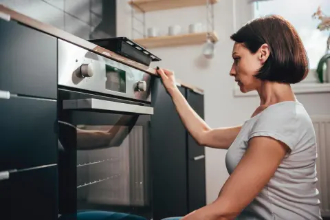 Donna controlla il display del suo forno a gas o elettrico prima di iniziare a cucinare.